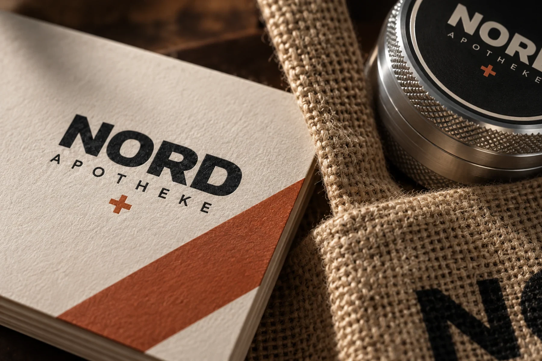 NORD APOTHEKE als fiktive Beispielmarke auf Papier, Jutestoff und Metall-Grinder