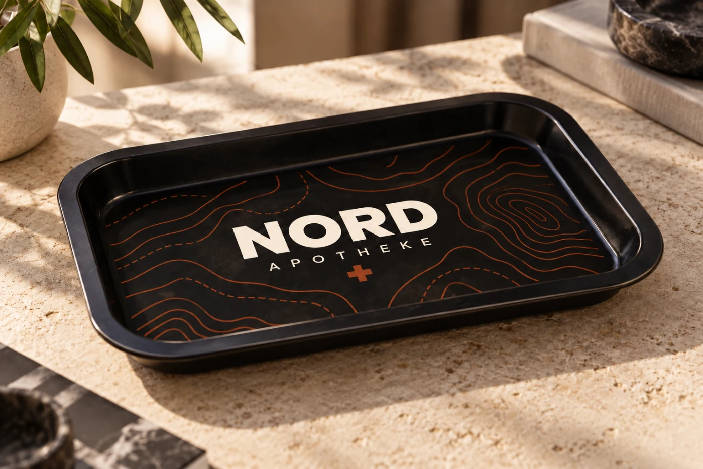 Schwarzes Metall-Tray mit fiktivem NORD Apotheke Branding auf einer hellen Oberfläche